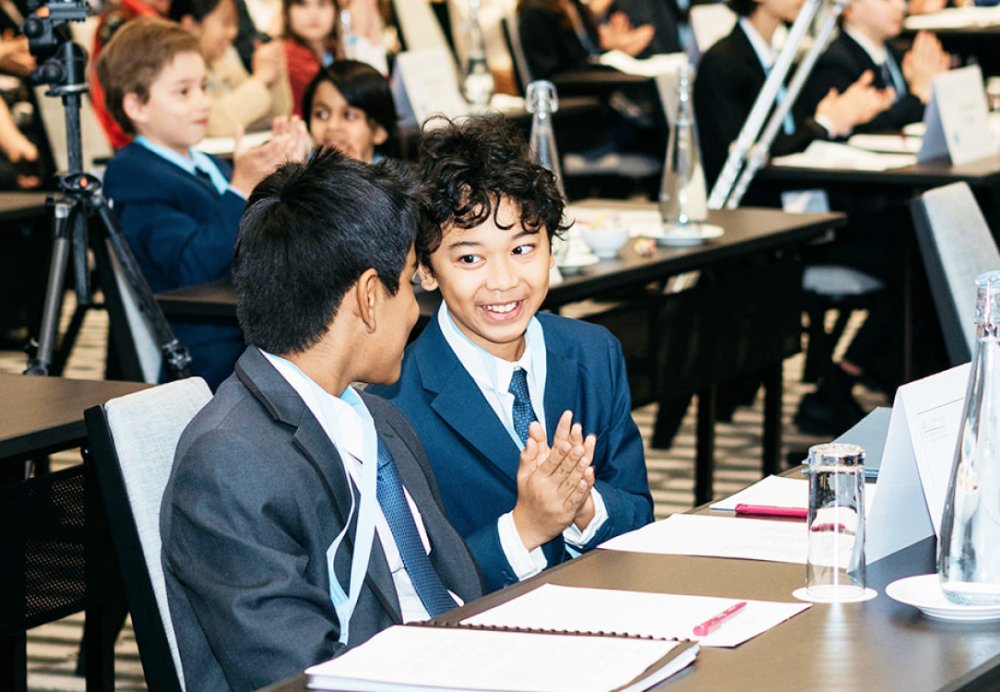 Two children sitting next to each other at a desk smiling